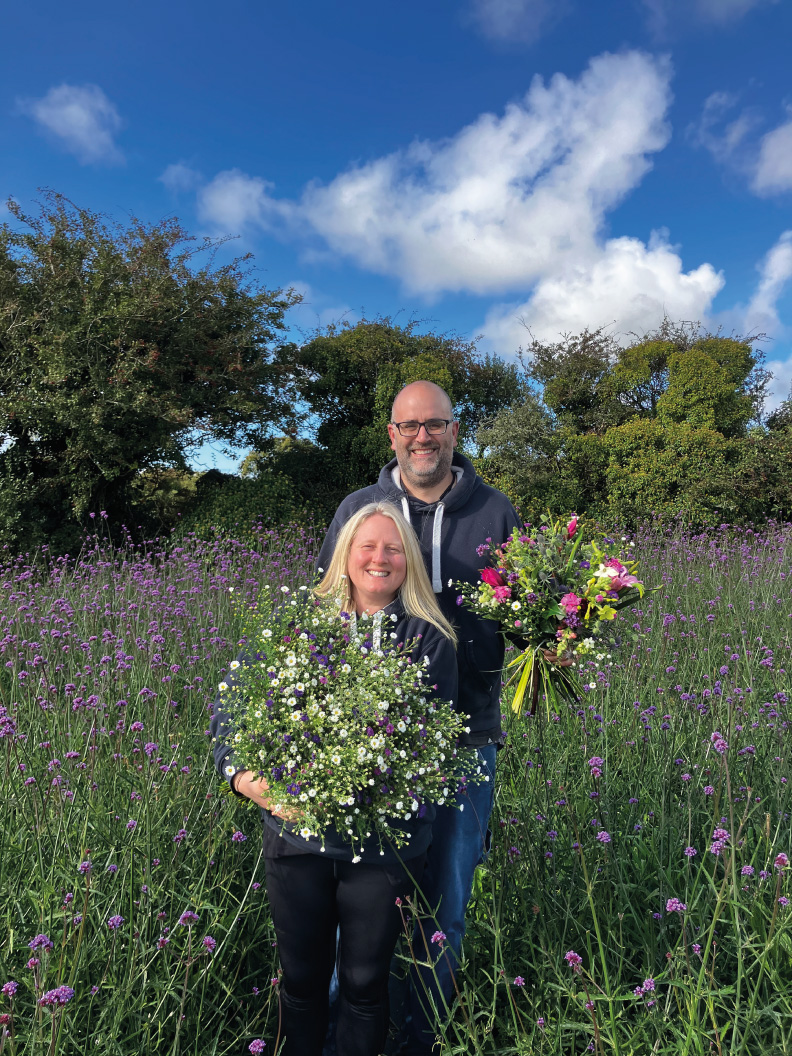 Beth and Simon standing in a field of flowers